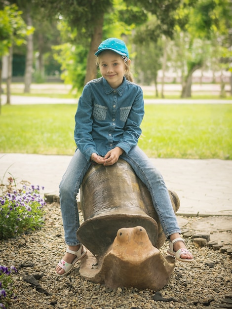 La jeune fille dans la casquette de baseball et les vêtements en jean à cheval sur la forme de la cochlée.