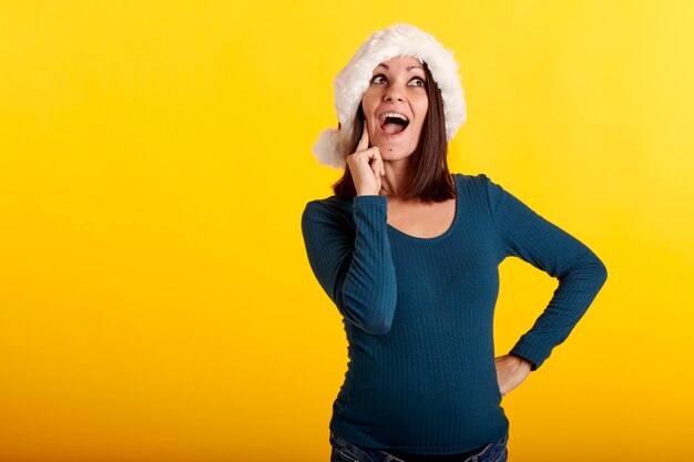 Une jeune fille dans un chapeau de père Noël avec un fond jaune