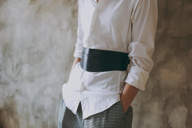 Jeune fille dans une chemise de bureau blanche essayant une ceinture en cuir