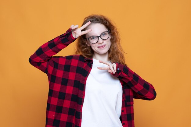 Photo jeune fille dans une chemise à carreaux avec des lunettes sur fond orange