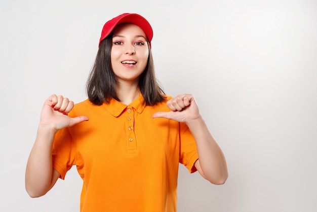 Photo jeune fille dans une chemise lumineuse gestes avec les deux mains sur elle-même