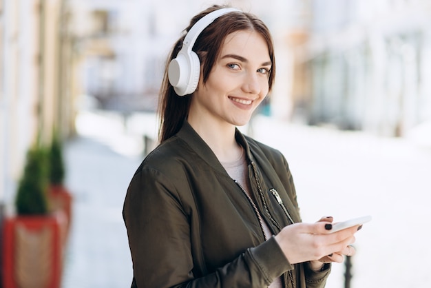 Jeune fille dans un collier et un téléphone dans ses mains, regardant la caméra.