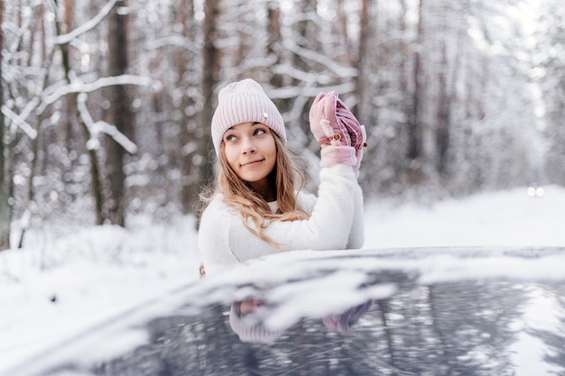 Photo jeune fille dans la forêt d'hiver sourit et lève les yeux dans la voiture
