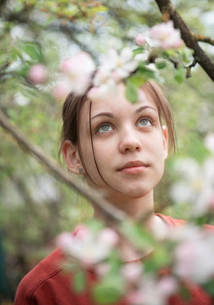 Une jeune fille dans un jardin fleuri regarde les arbres en fleurs