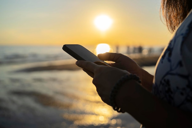 Jeune fille dans un manteau blanc en soie tenant un téléphone intelligent