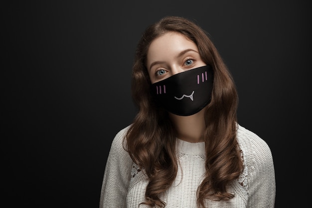 Jeune fille dans un masque sur un fond sombre