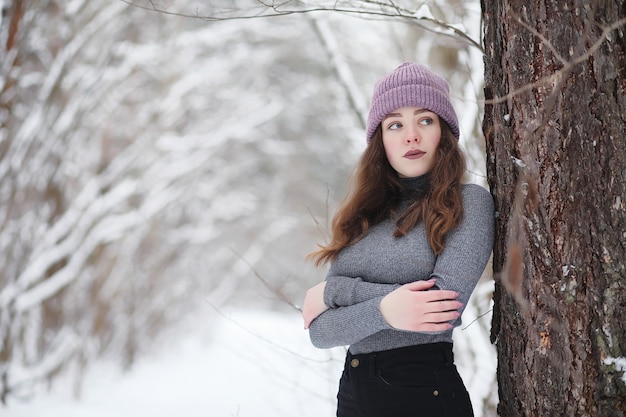 Une jeune fille dans un parc d'hiver lors d'une promenade. Vacances de Noël dans la forêt d'hiver. La fille aime l'hiver dans le parc.