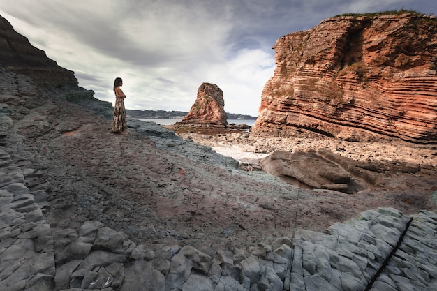 Jeune fille dans un paysage rocheux sur la côte.