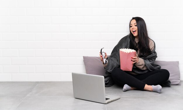 Jeune fille dans une pièce avec des lunettes 3d et tenant un gros seau de pop-corn