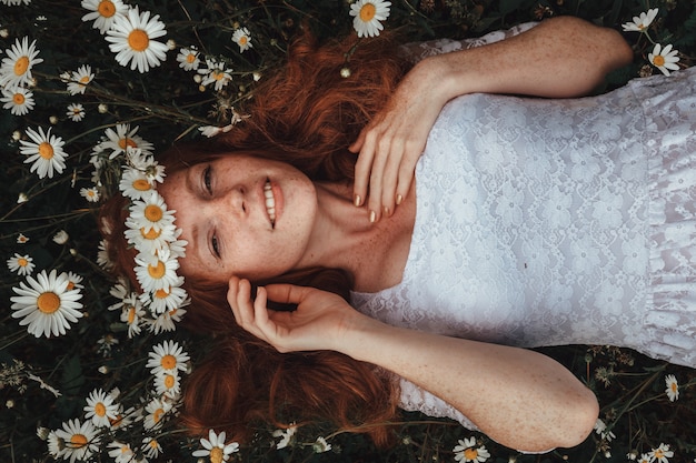 jeune fille dans une robe blanche dans le champ de camomille