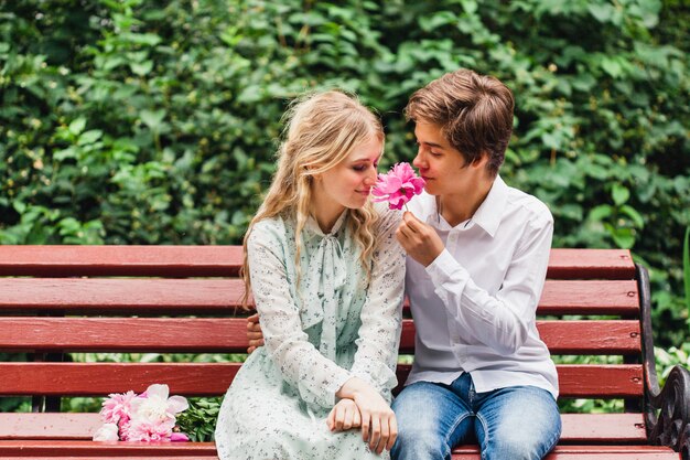 Une jeune fille dans une robe légère en été se dresse et détient des fleurs, pivoines, un bouquet, un cadeau, une date, l'attente, un banc, les amoureux,