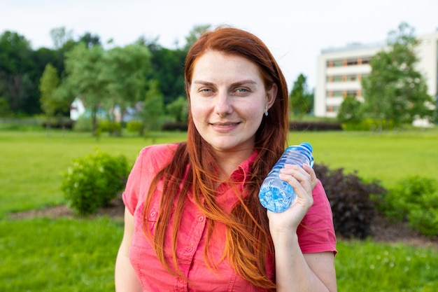 Jeune fille dans des vêtements d'été brillants est titulaire d'une bouteille d'eau en plastique