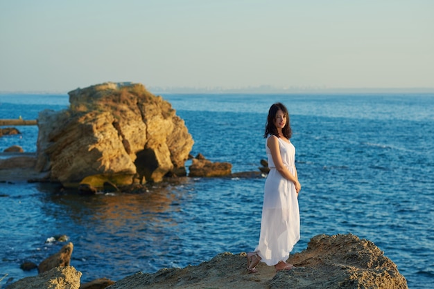 Jeune fille debout sur le rocher dans la mer d&#39;été bleu.
