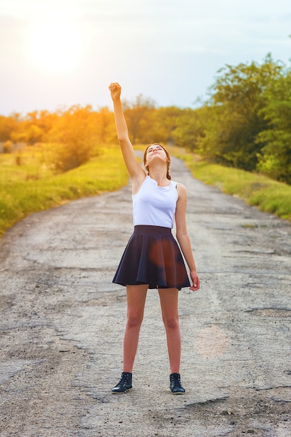 Jeune fille debout sur la route avec sa main levée, le concept de réussite.
