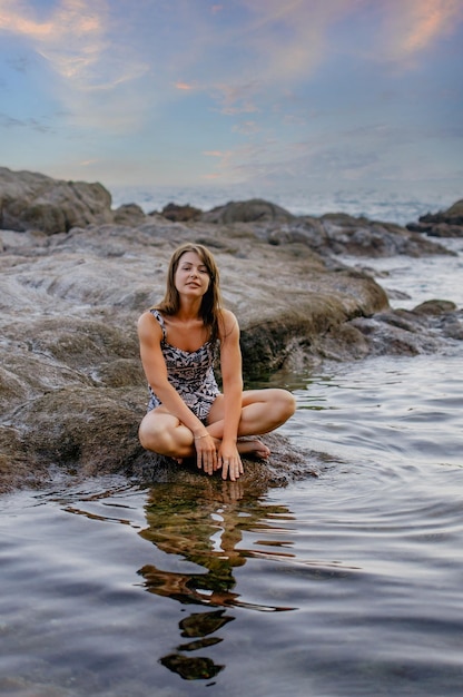 Jeune fille détendue assise sur la côte de la mer