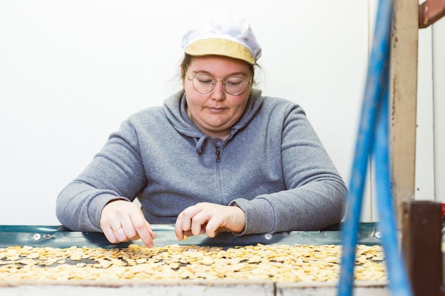 Jeune fille devant un tapis roulant sélectionnant des haricots