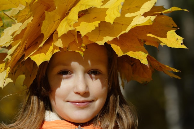 Jeune fille avec diadème de feuilles d'érable jaune au parc