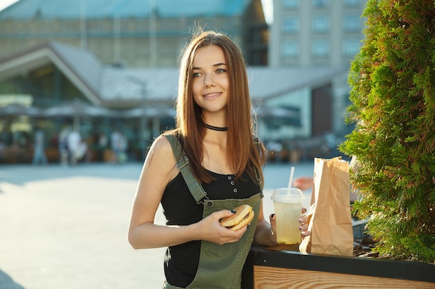 Une jeune fille dîne fast-food sur la place de la ville