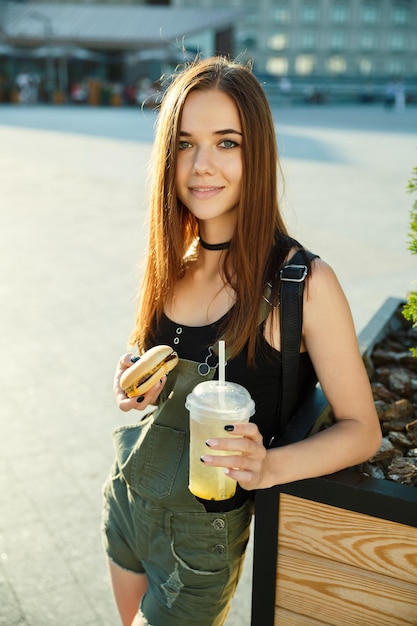 Une jeune fille dîne fast-food sur la place de la ville