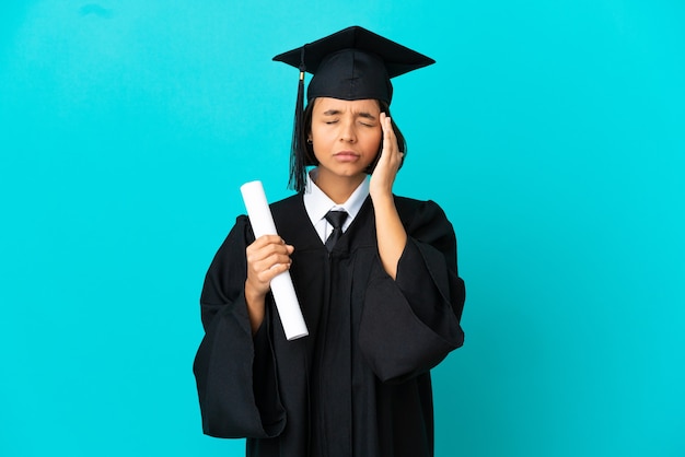 Jeune fille diplômée de l'université sur fond bleu isolé avec maux de tête