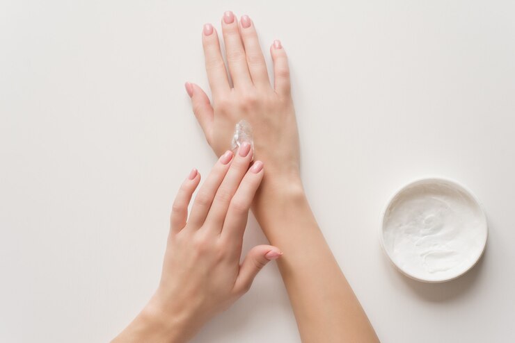 La jeune fille distribue de la crème hydratante sur ses mains.