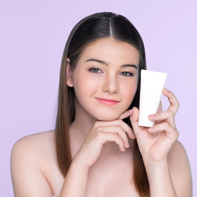 Jeune fille dodue charmante avec un tube de lotion de maintien de beauté naturelle