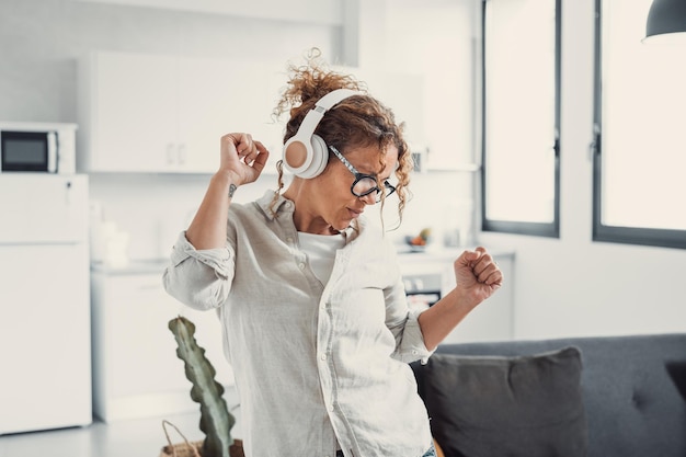 Photo une jeune fille du millénaire enjouée portant des écouteurs s'amuse en se déplaçant en écoutant de la musique se détend dans le salon
