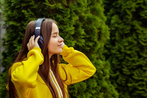 Jeune fille écoutant un lecteur MP3 dans la rue avec un casque, souriant