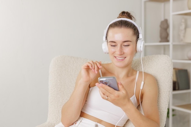 Jeune fille écoute de la musique dans des écouteurs avec téléphone à la maison concept de vacances de temps libre