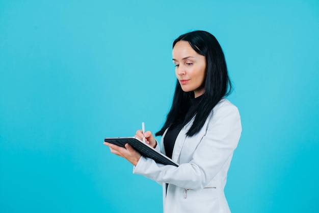 La jeune fille écrit le texte sur la tablette sur le fond bleu