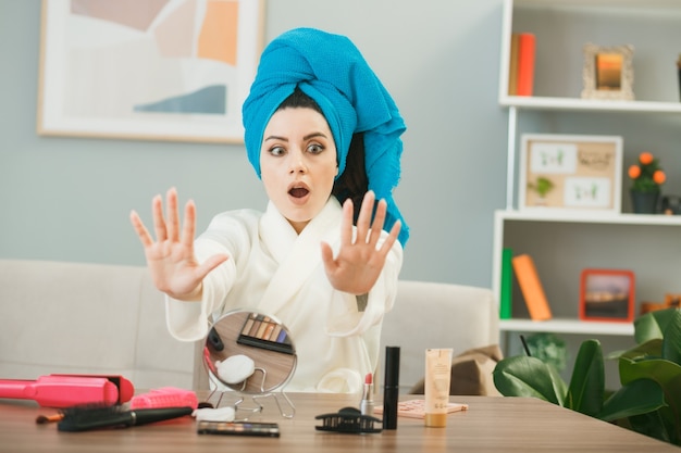 Jeune fille effrayée enveloppée de cheveux dans des ongles en gel sec, assis à table avec des outils de maquillage dans le salon