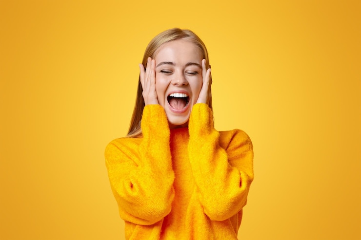 Photo une jeune fille émotionnelle étonnée se touche le visage d'excitation.