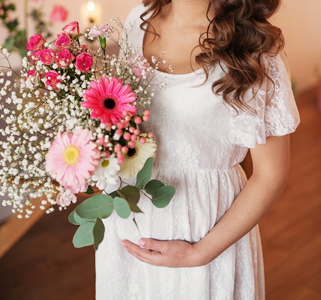 Jeune fille enceinte sur un fond clair avec des fleurs