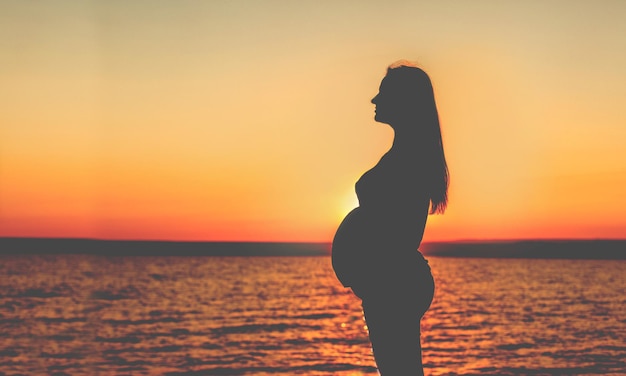 Jeune fille enceinte sur la silhouette de la plage