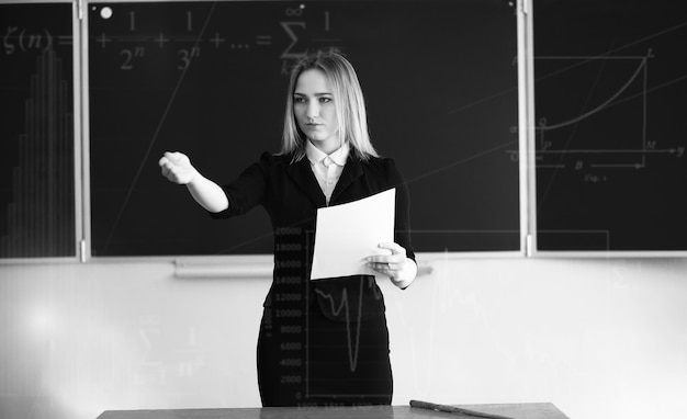 Jeune fille enseignante à l'école primaire en classe devant blackboardxA