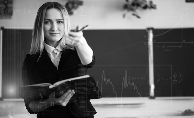 Jeune fille enseignante à l'école primaire en classe devant blackboardxA