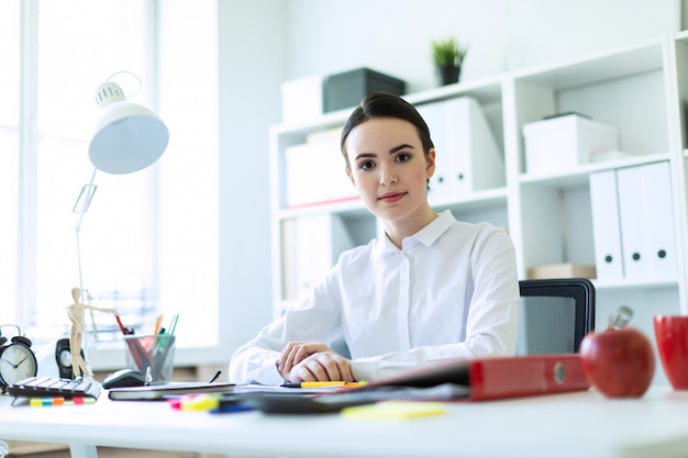 Une jeune fille est assise au bureau d'ordinateur dans le bureau.