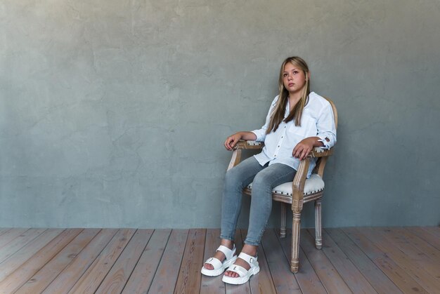 Une jeune fille est assise sur une chaise légère