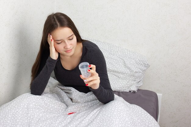 Jeune fille est assise sur un lit avec une banque pour analyse