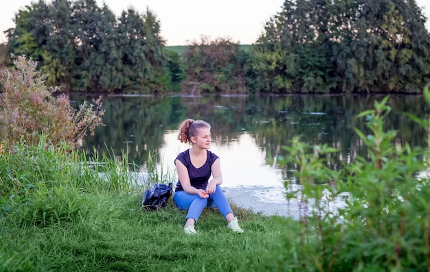 Une jeune fille est assise sur la rive et admire la nature. Mode de vie sain, rester dans la nature
