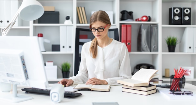 Une jeune fille est assise à une table dans le bureau et tient un marqueur jaune à la main.