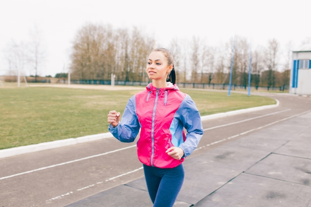 Une jeune fille est engagée dans le sport en faisant un jogging autour du stade