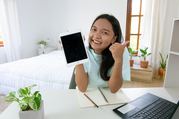 Jeune fille étudiant avec un ordinateur portable dans la chambre à coucher à la maison