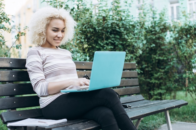 Une jeune fille étudiant en plein air à l&#39;extérieur est assise sur le banc