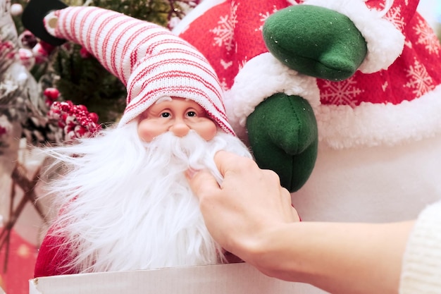 La jeune fille examine et touche la barbe d'un jouet du marché de Noël du Père Noël dans le centre commercial