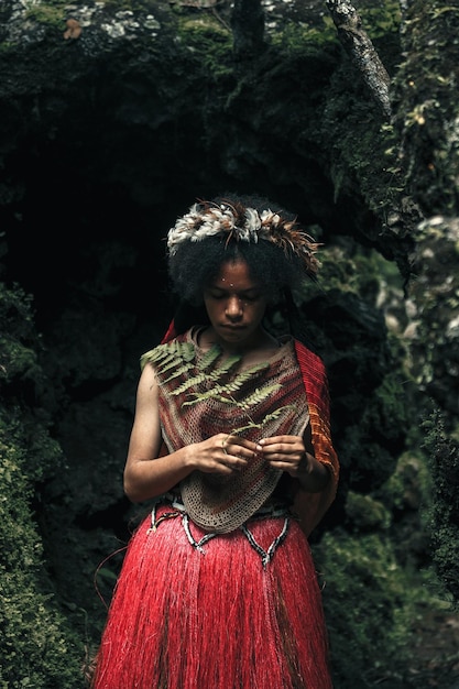 Une jeune fille exotique de Papouasie de la tribu Dani en vêtements traditionnels regarde le feuillage vert à la main dans le