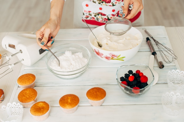 Jeune fille faisant de la crème pour les petits gâteaux.