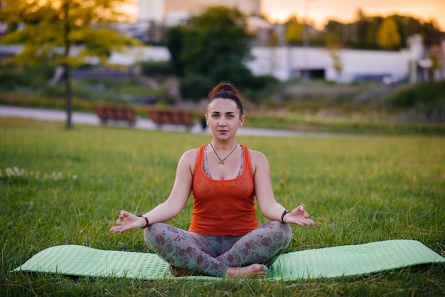 Jeune fille faisant du yoga en plein air, dans le parc au coucher du soleil. Mode de vie sain