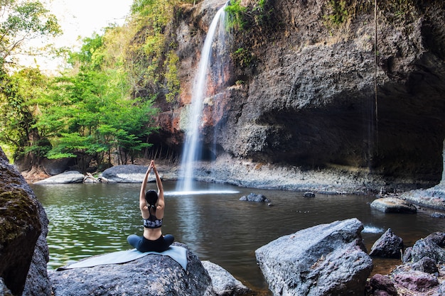 Jeune fille faisant du yoga près d'une cascade