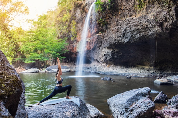 Jeune fille faisant du yoga près d'une cascade